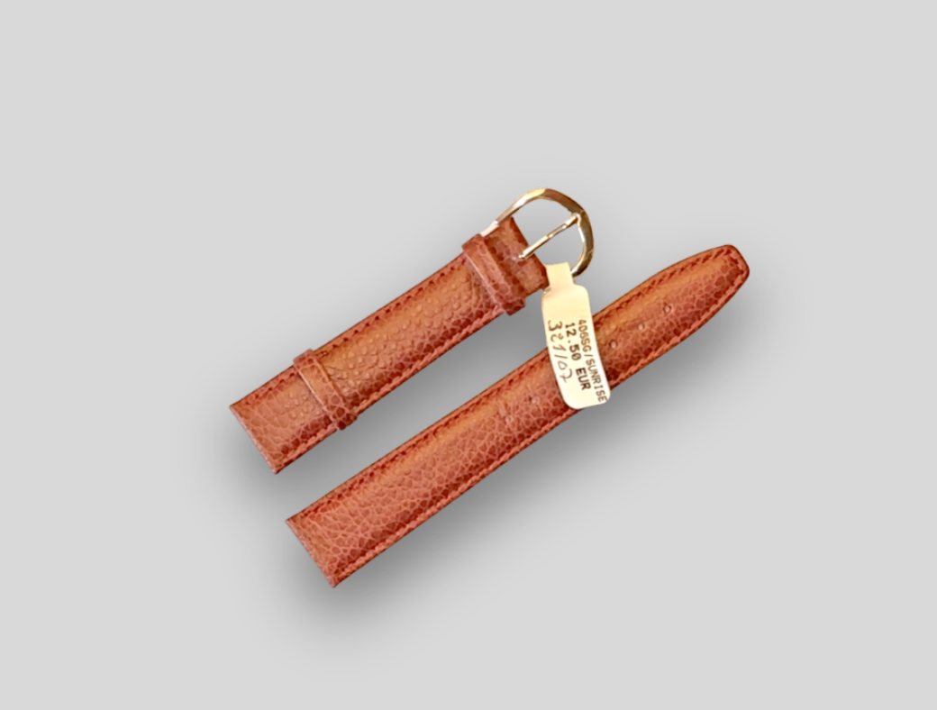 Brown leather watch strap with gold buckle on a gray background