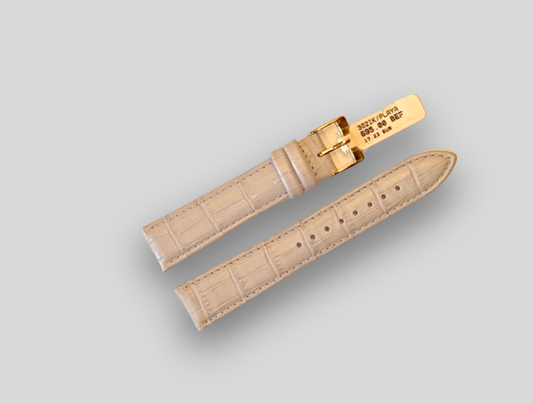 Beige watch strap with gold buckle on a light gray background