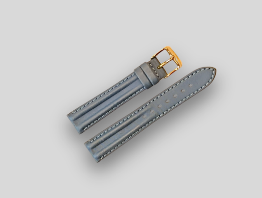 Gray watch strap with gold buckle on a light gray background