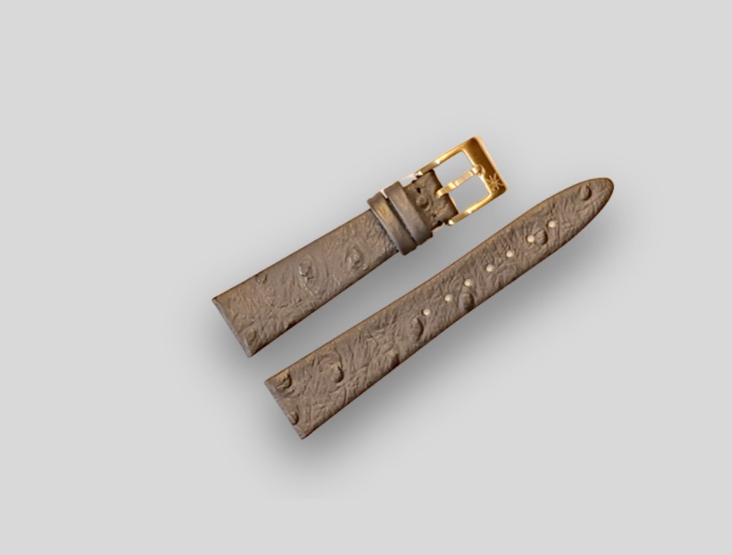 Brown textured watch strap with gold buckle on a light gray background