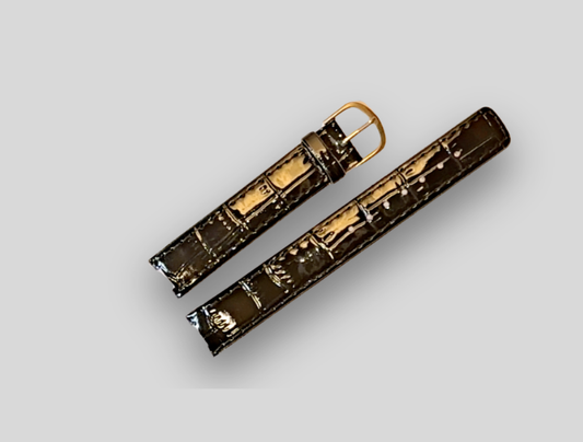 Brown crocodile-patterned leather strap with gold buckle on a light gray background