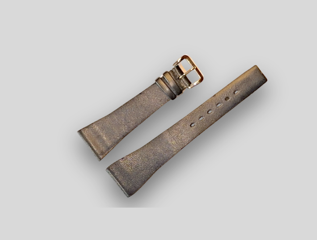 Brown leather watch strap with gold buckle on a light gray background