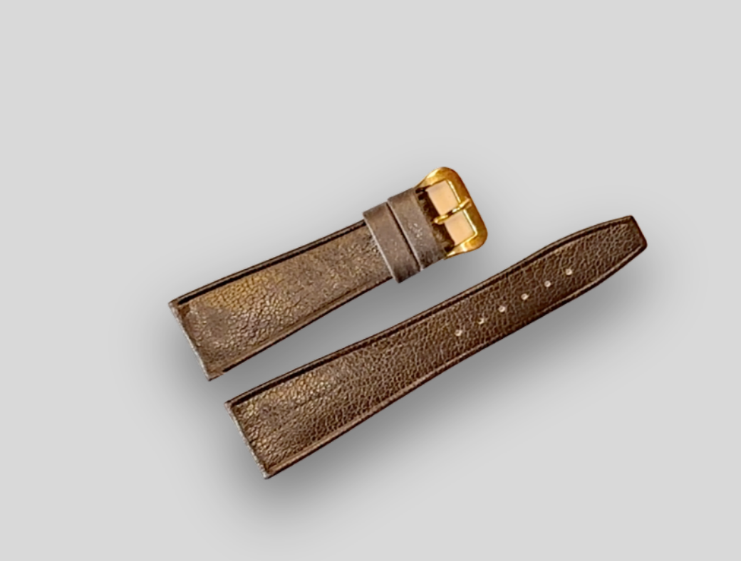 Brown leather watch strap with gold buckle on a light gray background