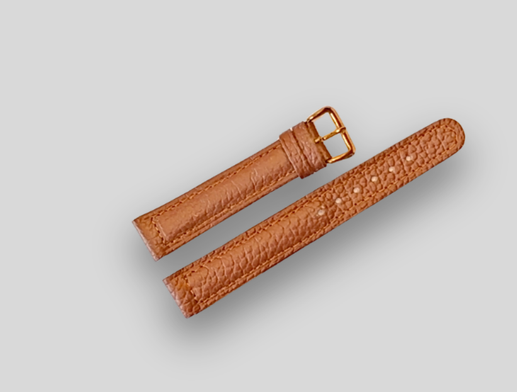 Brown leather watch strap with gold buckle on a light gray background