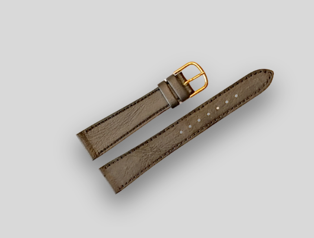 Brown leather watch strap with gold buckle on a light gray background