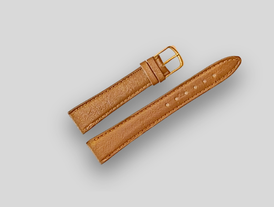 Brown leather watch strap with gold buckle on a light gray background